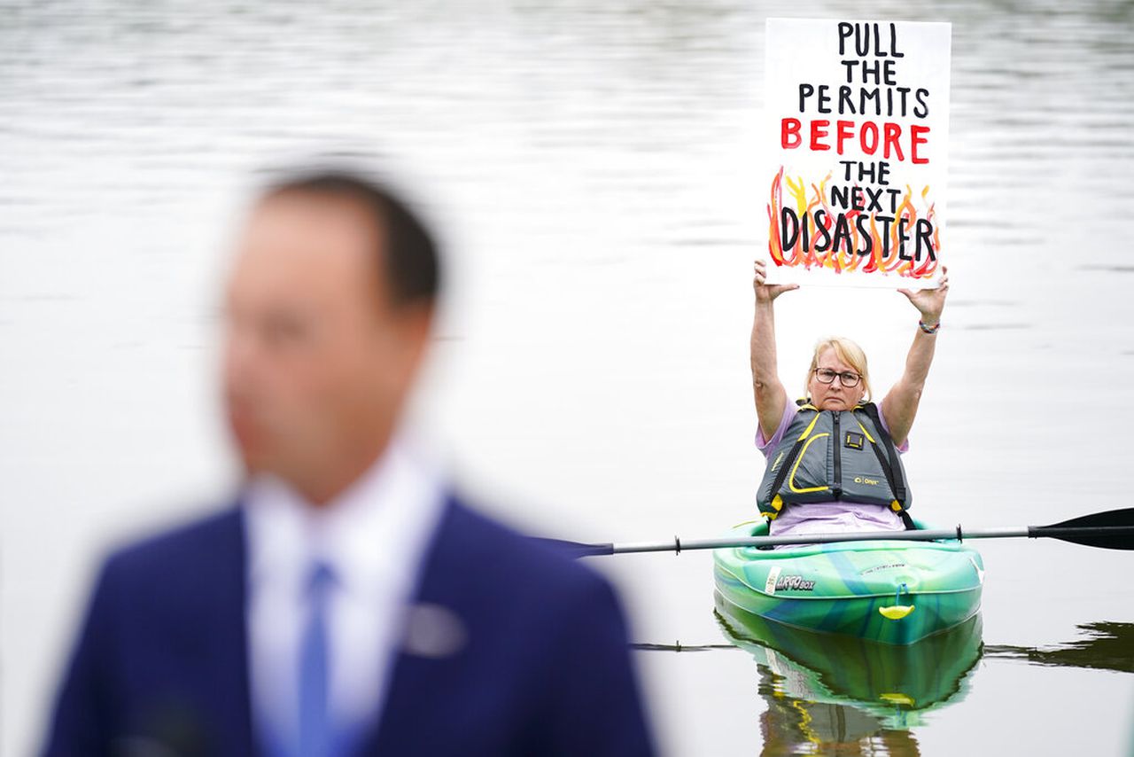 Libby Madarasz displays a placard as Pennsylvania Attorney General Josh Shapiro speaks during a news conference at Marsh Creek State Park in Downingtown, Pa., Tuesday, Oct. 5, 2021. Shapiro filed criminal charges Tuesday against the developer of a problem-plagued pipeline that takes natural gas liquids from the Marcellus Shale gas field to an export terminal near Philadelphia. (AP Photo/Matt Rourke)